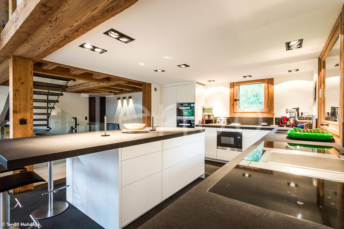 A kitchen with white cabinets and black counter tops