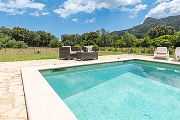 A swimming pool with chairs and a mountain in the background