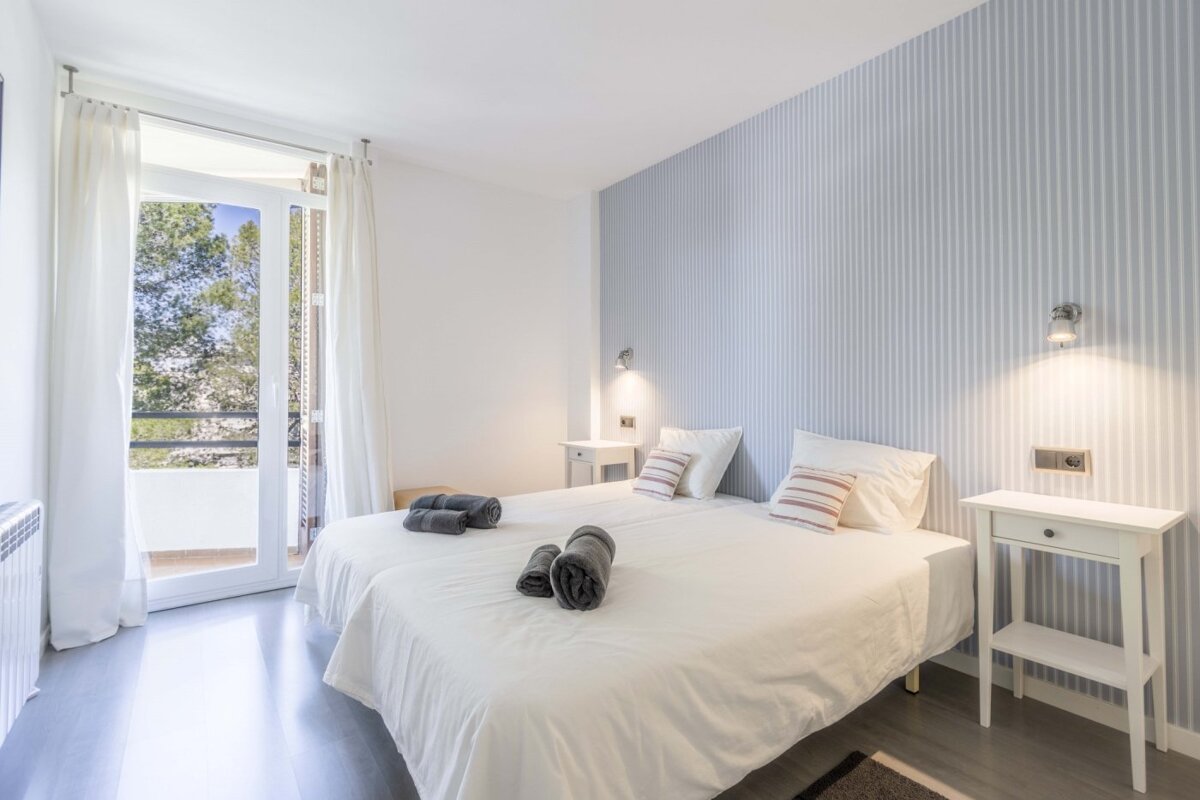 A bedroom with two beds and striped wallpaper