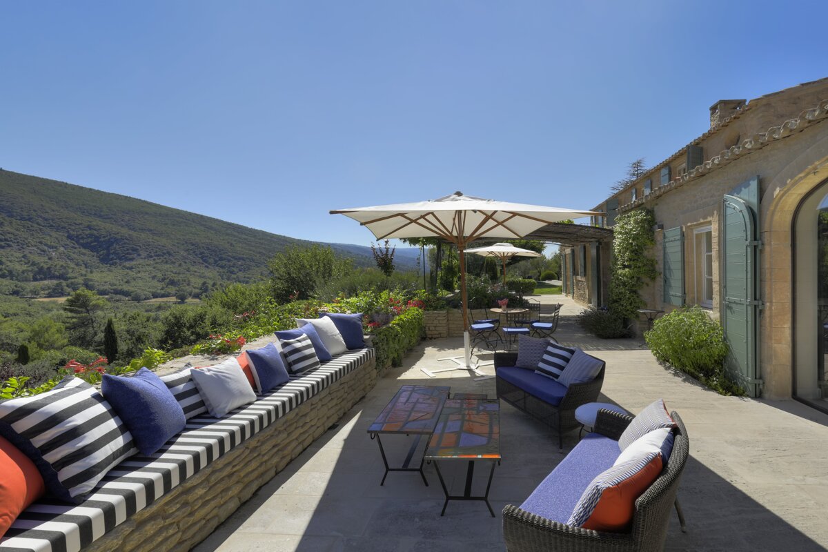 A patio with a couch and umbrellas with a mountain in the background