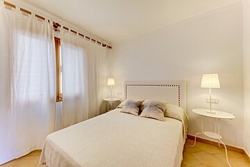 A bedroom with a bed and two lamps