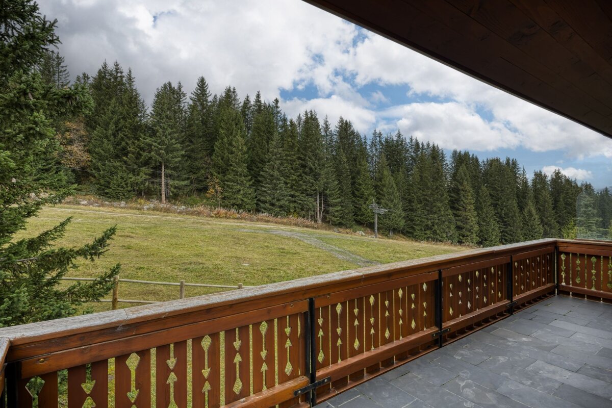 A balcony with a wooden railing overlooking a forest