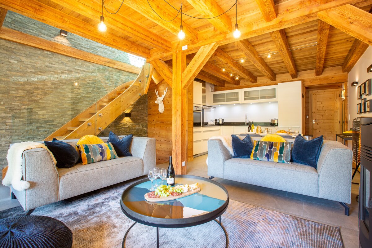 A living room with two couches and a table with a bottle of wine on it