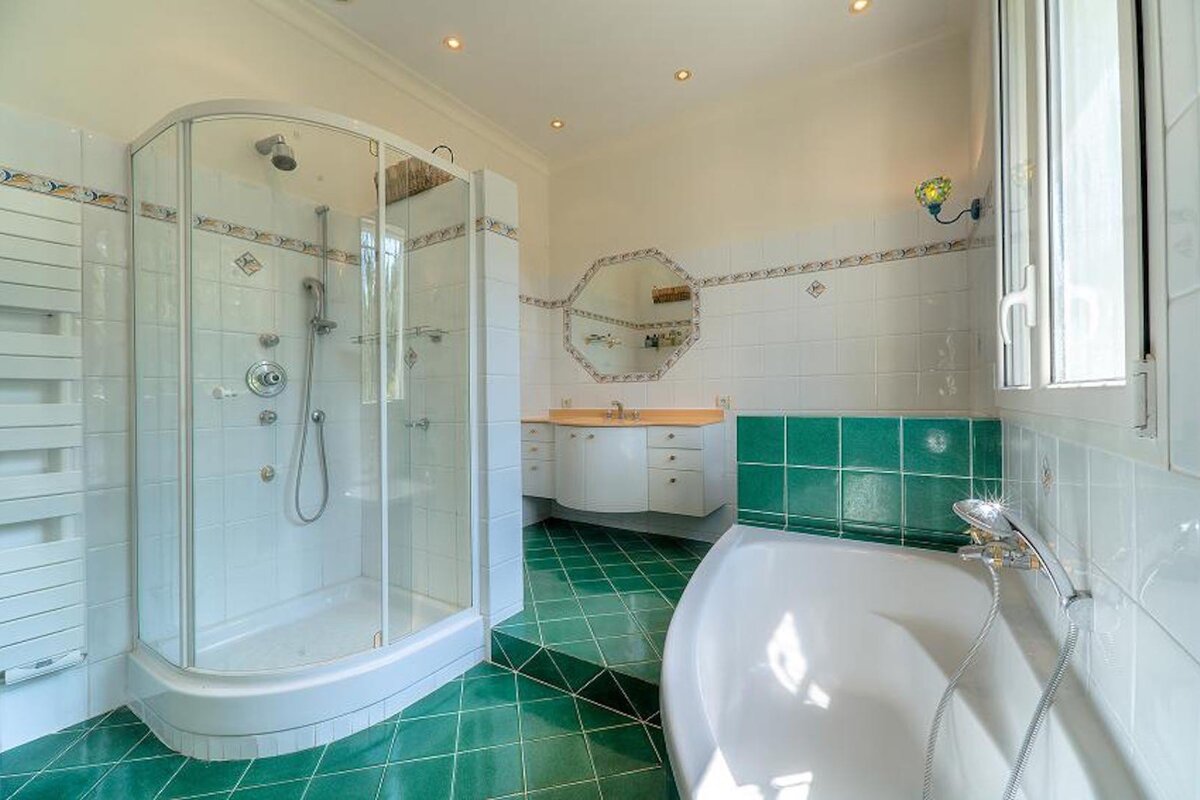 A bathroom with green tiles and a tub and shower