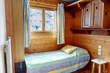 A wooden bedroom with a single bed and a window