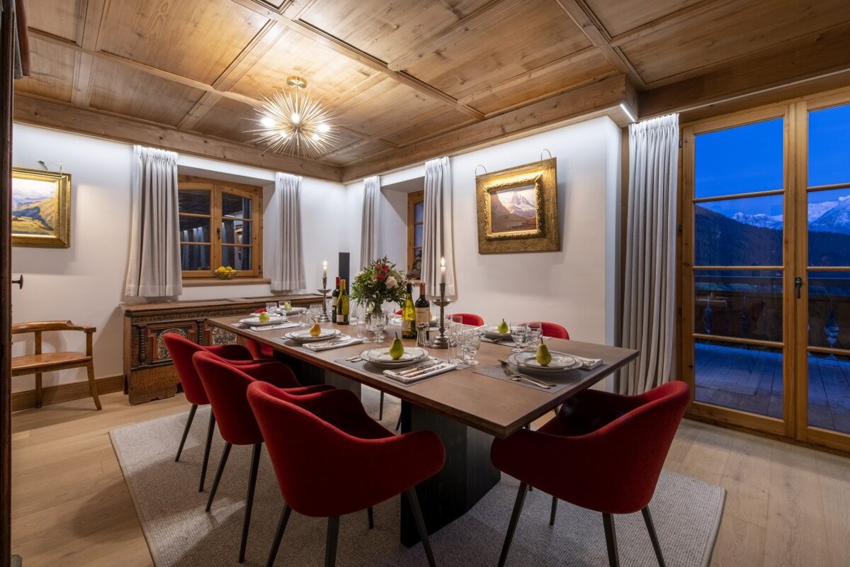 A dining room with a long table and red chairs