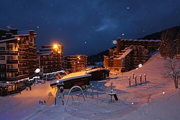 A snowy ski resort at night with a sign that says ' altitude ' on it