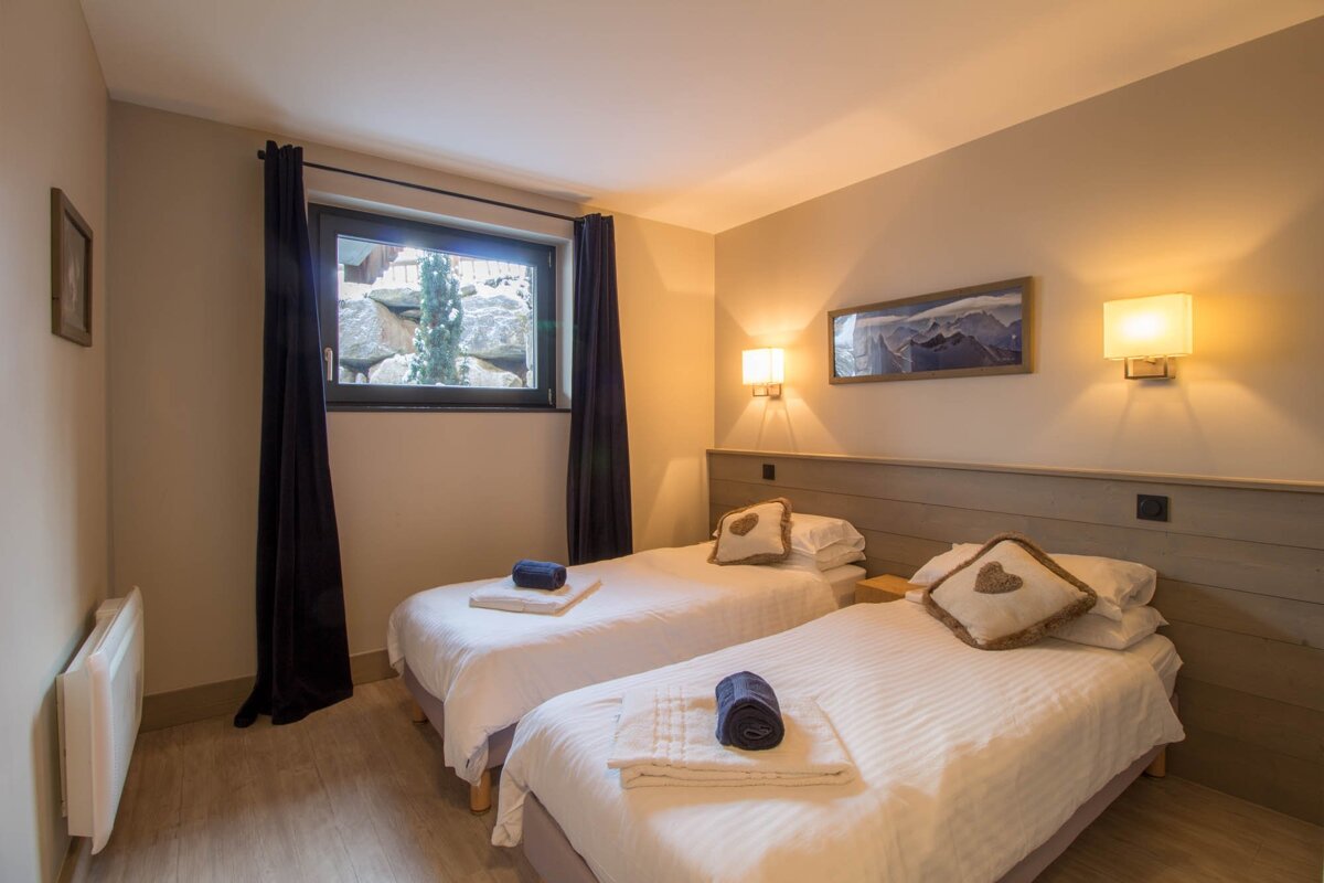 A bedroom with two twin beds and a window