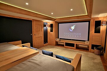 A luxurious wood-paneled home cinema with a large screen displaying 