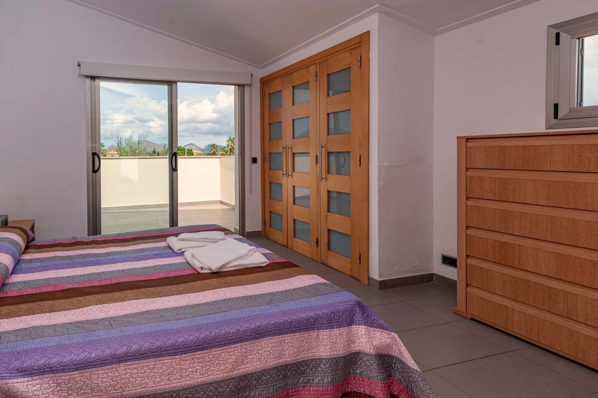 A bedroom with a striped bed and a dresser