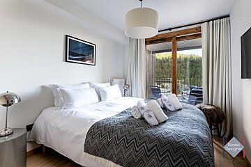 A bedroom with a rental designer logo on the corner