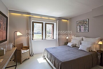 A bedroom with a large bed and a picture on the wall that says maison janssens immobilier