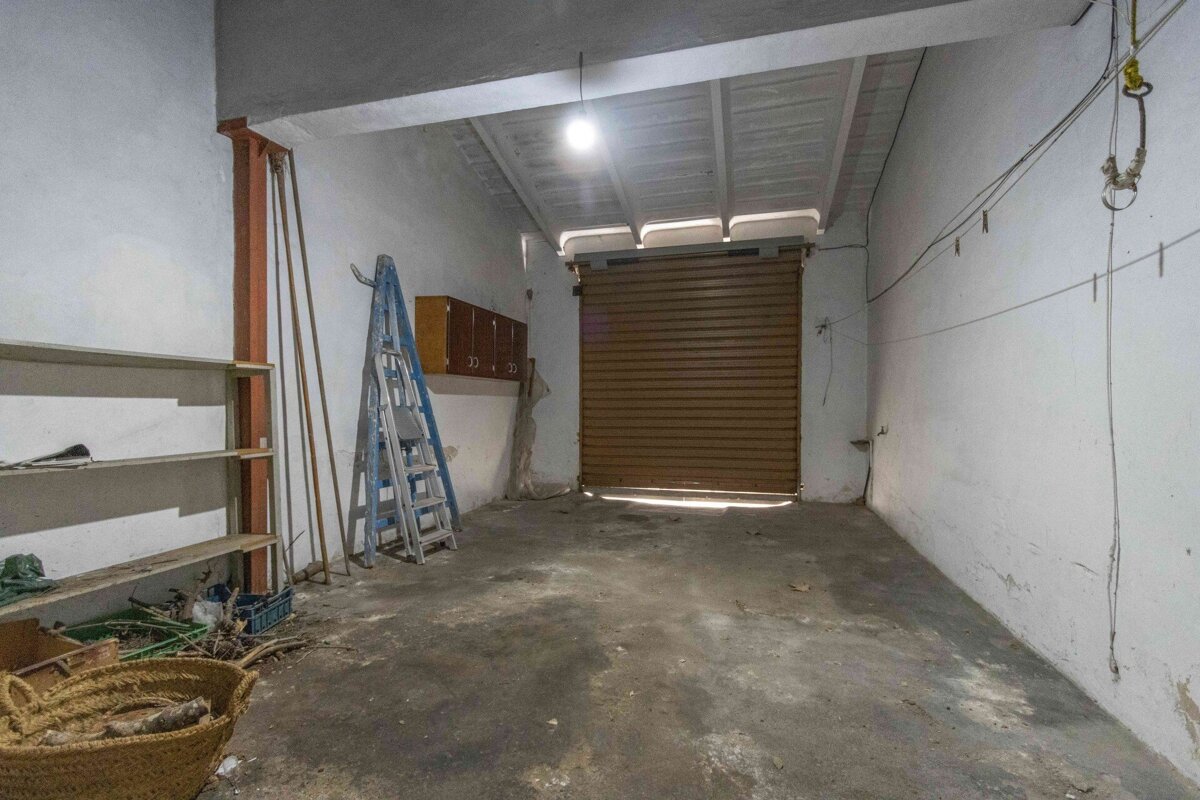 An empty garage with a ladder and a basket on the floor