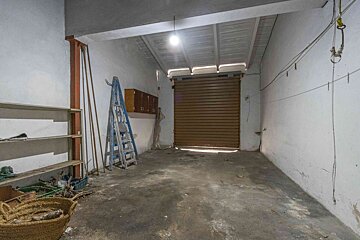 An empty garage with a ladder and a basket on the floor