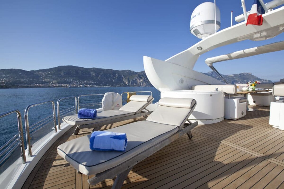 Two lounge chairs on the deck of a boat with a satellite dish on top