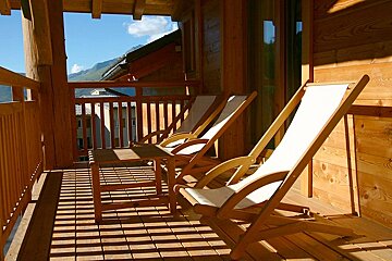 A wooden balcony with chairs and a table
