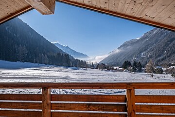 A view of a snowy mountain valley from a balcony
