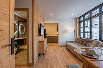 A living room with a couch and a television on the wall