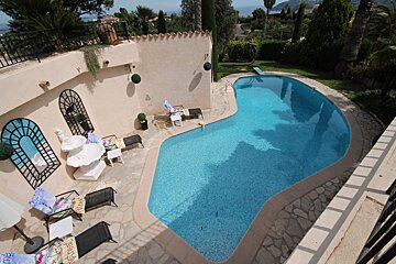 A large swimming pool is surrounded by chairs and a table with a sign that says ' i love you ' on it