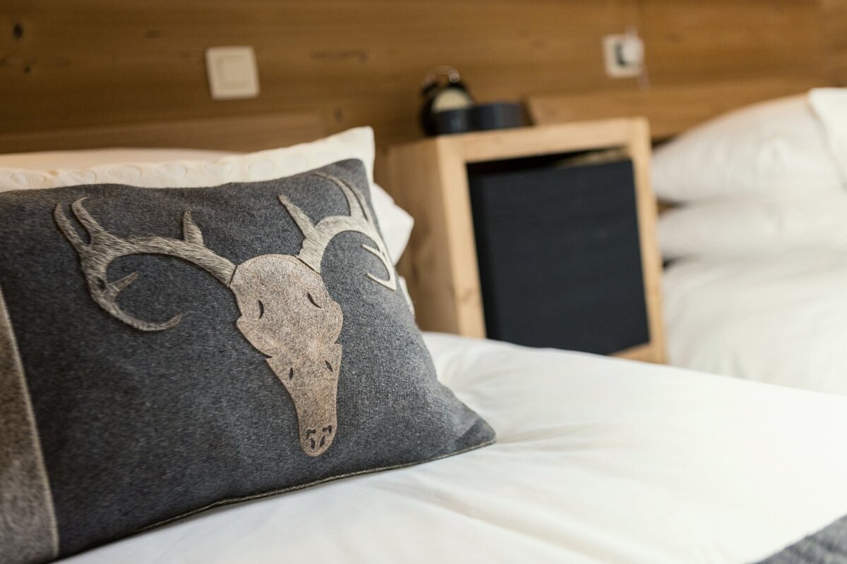 A pillow with a deer skull on it sits on a bed