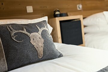 A pillow with a deer skull on it sits on a bed