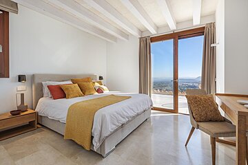 A bedroom with a large bed and a sliding glass door
