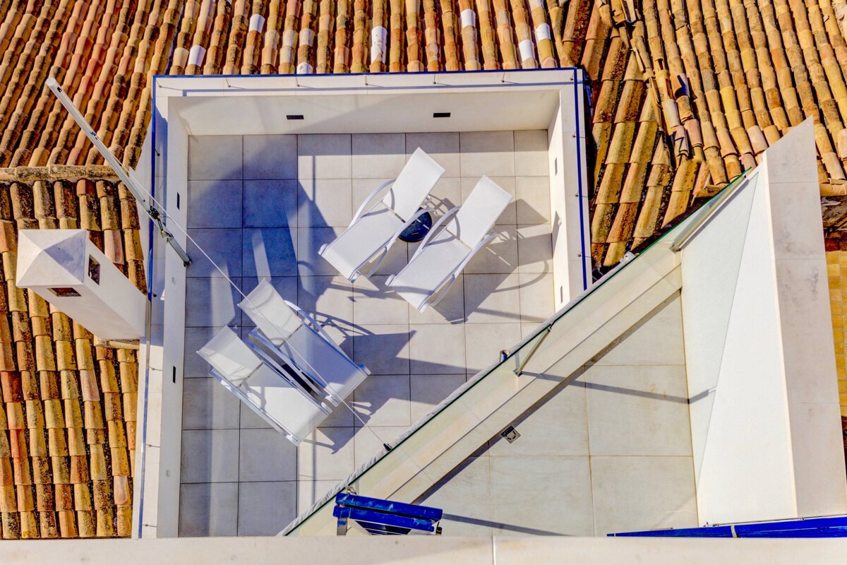 An aerial view of a rooftop deck with white chairs