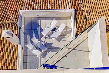 An aerial view of a rooftop deck with white chairs
