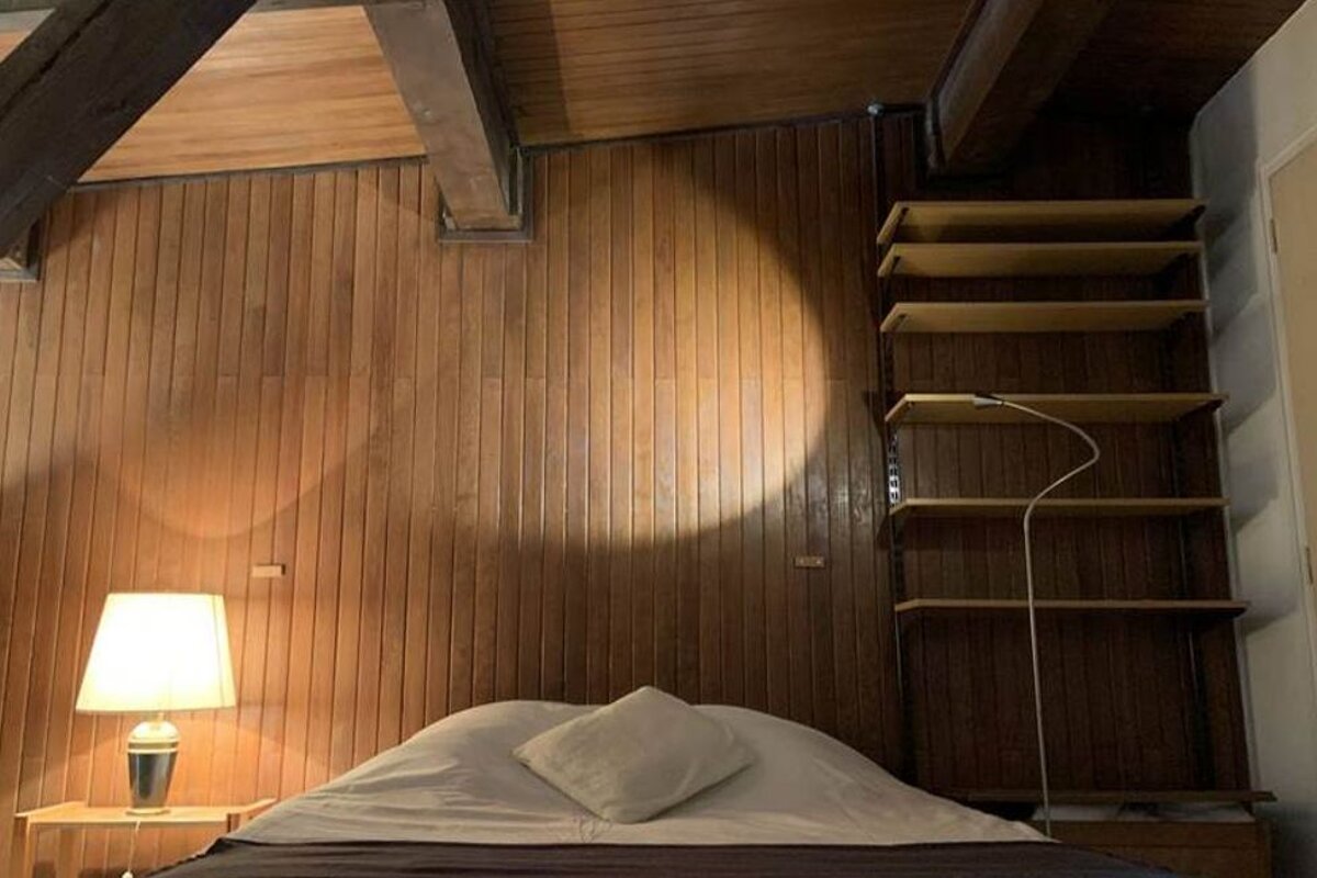 A bedroom with a bed a lamp and shelves