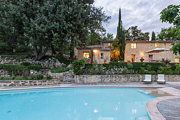 A large stone house with a swimming pool in front of it