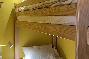 A bunk bed with a yellow wall behind it