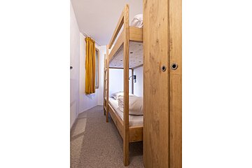 A bunk bed with a yellow curtain behind it