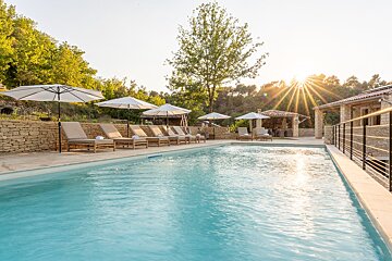 A large swimming pool surrounded by chairs and umbrellas