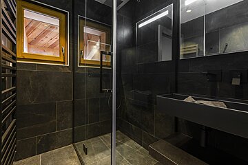 A bathroom with a walk in shower and a sink