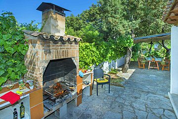 A bottle of olive oil sits on a counter next to a grill