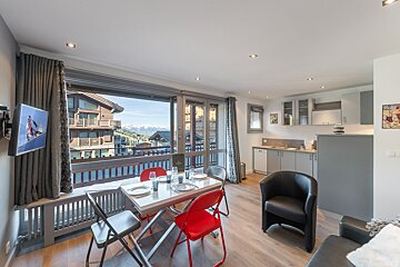 A living room with a table and chairs and a tv
