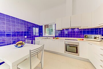 A kitchen with purple tiles and white cabinets
