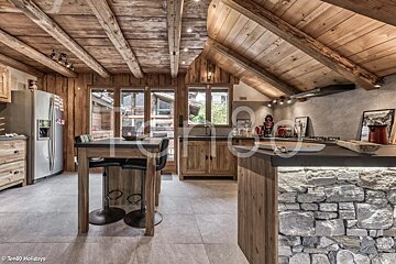 A rustic alpine kitchen with exposed wooden beam ceilings, a stone-clad island, and wooden cabinetry.