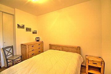 A bedroom with a bed a dresser and a chair