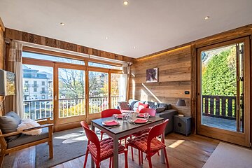 A living room with a dining table and red chairs