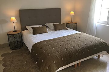 A bed with a brown blanket and pillows in a bedroom