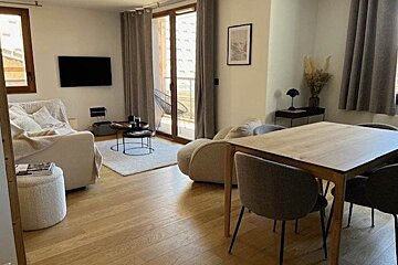 A living room with a table and chairs and a flat screen tv