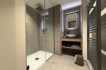 A bathroom with a walk in shower and a sink