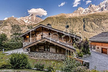A photo of a chalet with mountains in the background
