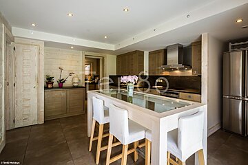 A kitchen with a stainless steel refrigerator and a table with a glass top