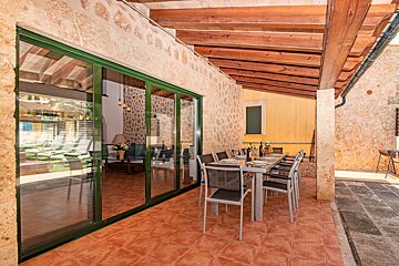 A patio with a table and chairs under a wooden roof