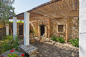 A patio with a table and chairs under a thatched roof