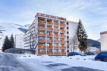 A building with a lot of balconies is surrounded by snow