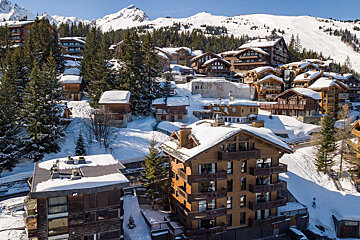 Snow covered buildings in a ski resort with a mountain in the background