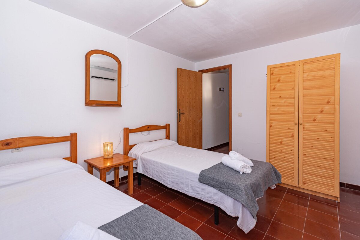 A bedroom with two beds and a mirror on the wall